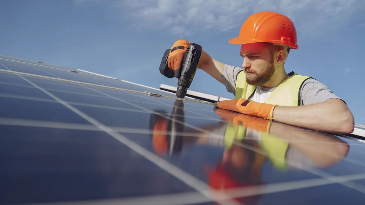 Tehnician montând un panou fotovoltaic cu bormașina