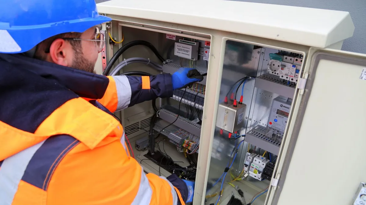 Electrician verificând un tablou electric exterior, ilustrând gradul de protecție IP