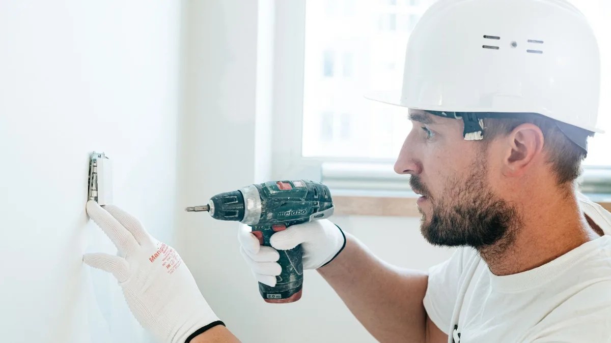 Instalator fotovoltaic autorizat, cu cască de protecție, montând un echipament electric