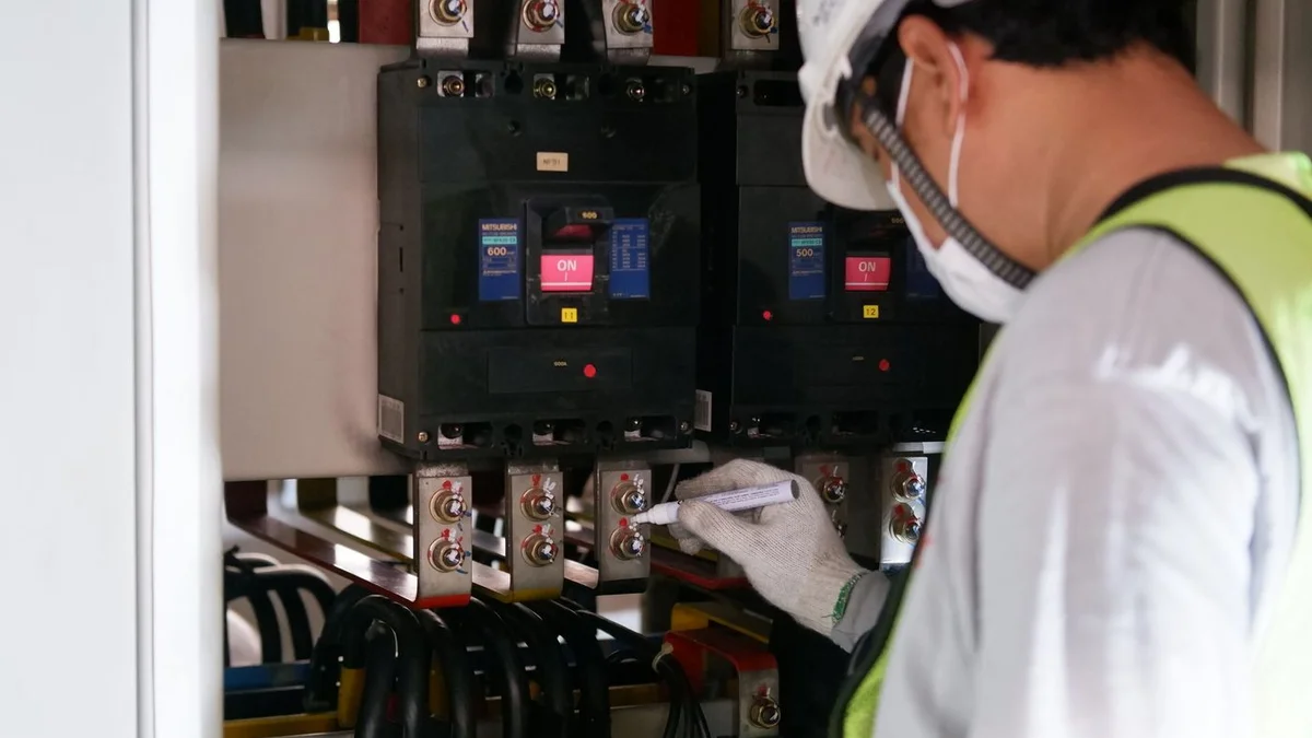 Tehnician verificând un tablou electric cu întrerupătoare industriale