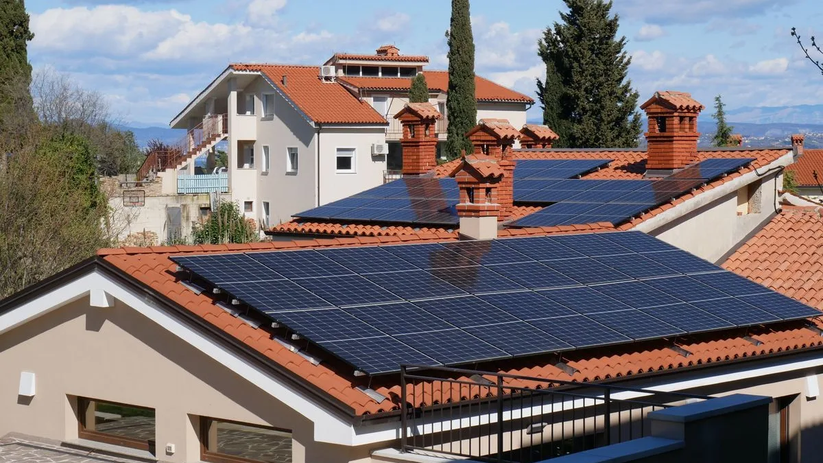 Case cu acoperiș de țiglă roșie și panouri fotovoltaice, într-o zonă rezidențială