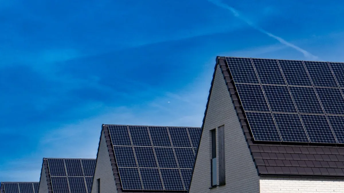 Acoperișuri de case acoperite cu panouri fotovoltaice negre, sub cer albastru