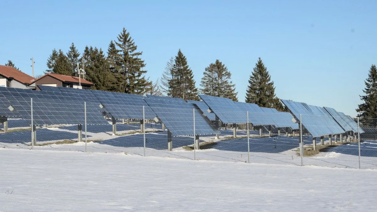 Panouri fotovoltaice montate pe sol, într-un câmp acoperit de zăpadă, într-o zi senină de iarnă