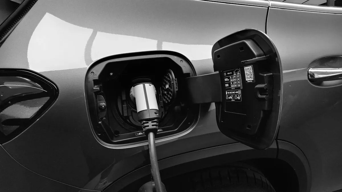 Mașină electrică în timpul încărcării, cu conectorul cablului introdus în priza de încărcare